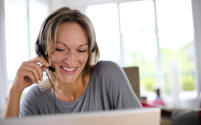 Portrait of woman with headset in front of laptop
